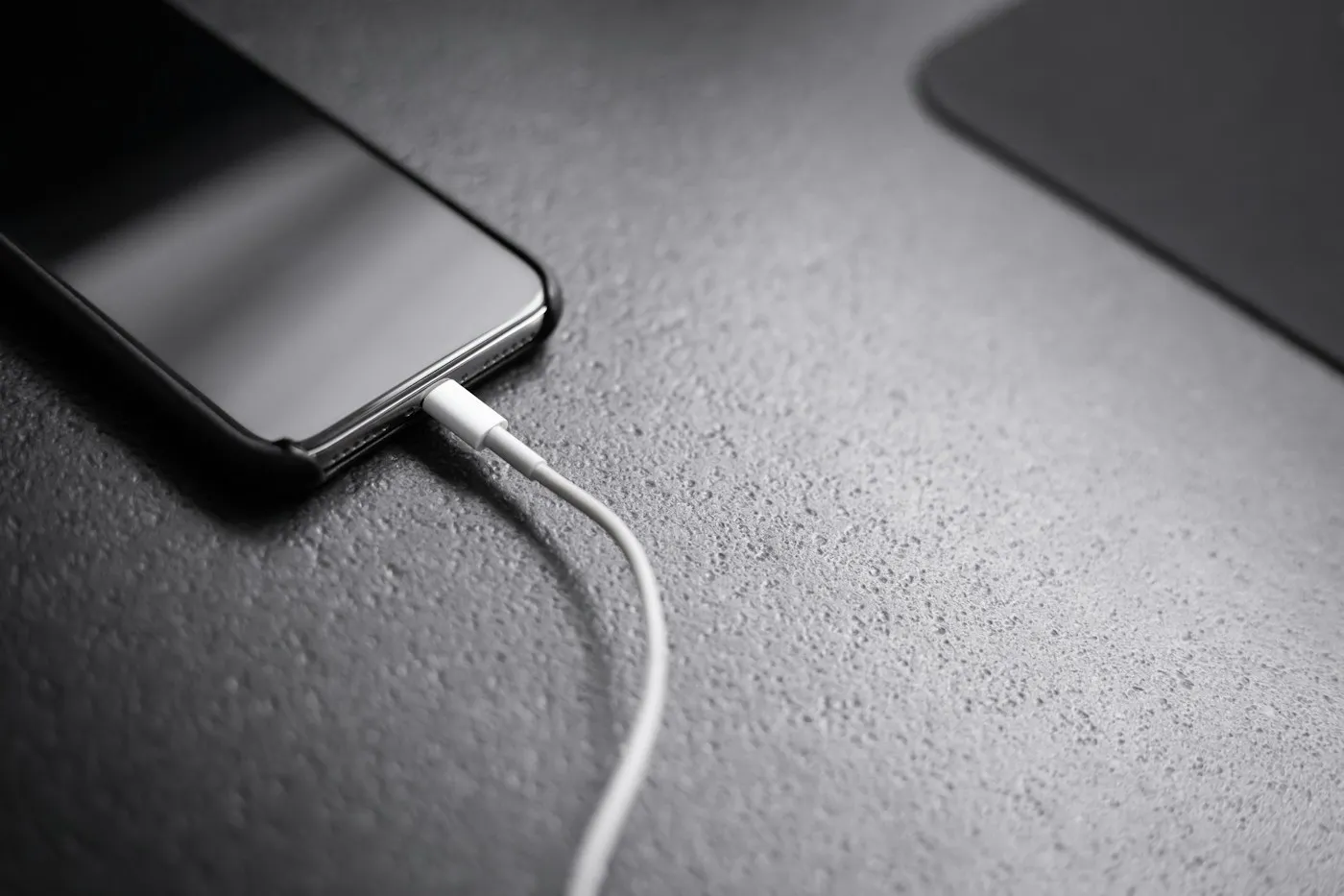 iPhone conectado a su cable de carga sobre una superficie gris oscura
